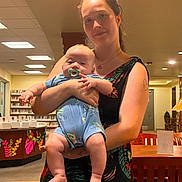 Ryder joined the competition — help win amazing prizes! woman, baby, indoor, holding, pacifier, smile, furniture, wooden_chair, library, decor, lighting, person, child, portrait, casual, clothing, happy, family, people, adult