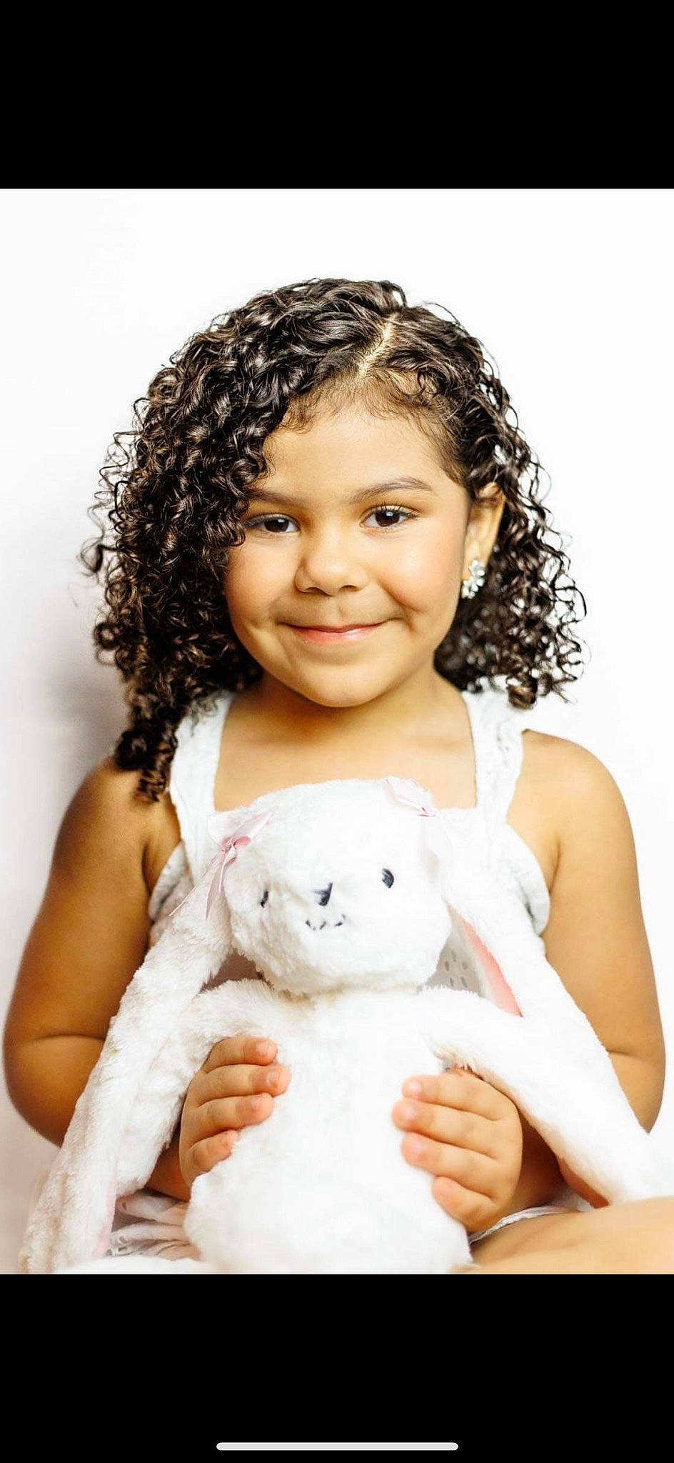 Kamryn is registered to the contest to win money with this photo: beauty, black_hair, cheek, child, eyelash, gesture, hair, happy, joy, nose, organ, person, photograph, ringlet, skin, sleeve, smile, stuffed_toy, teddy_bear, toddler