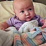 baby, infant, purple_clothing, blanket, crochet_blanket, pastel_colors, bed, headboard, soft_texture, curious_expression, chubby_cheeks, person, indoor, cozy, child, newborn, cute, face, cuddly, resting