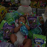 Raelynn is registered to the contest to win money with this photo: baby, candy, plush_bunny, decorative_grass, shopping_cart, packaging, child, toy_store, snack, colorful, retail, grocery, product_packaging, sitting, infant, cute, store_shelf, retail_display, playful, holding
