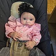 Gabriella participe au concours pour gagner de l'argent avec cette photo : baby, child, infant, pink_clothing, headband, flower, baby_carrier, checkered_pants, sitting, indoors, floor, face, hands, person, cute, young, portrait, looking, clothing, fabric