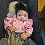 baby, child, infant, pink_clothing, headband, flower, baby_carrier, checkered_pants, sitting, indoors, floor, face, hands, person, cute, young, portrait, looking, clothing, fabric