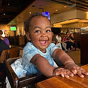 Noah joined the competition — help win amazing prizes! child, baby, toddler, high_chair, wooden_table, smile, joyful, restaurant, dining, people, face, eyes, hands, clothing, interior, ceiling_pipes, tv_screen, background, chair, infant