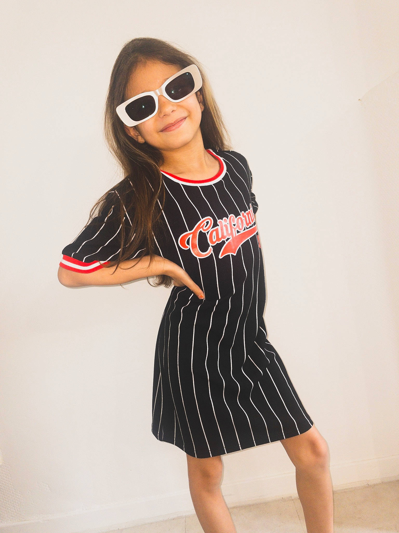 Kheira participe au concours pour gagner de l'argent avec cette photo : arm, black_hair, day_dress, fashion_design, fashion_model, gesture, goggles, joy, knee, long_hair, neck, one_piece_garment, pattern, person, sleeve, smile, sunglasses, t_shirt, thigh, vintage_clothing