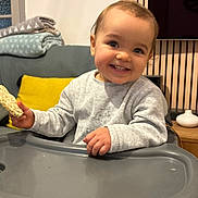 Luna a rejoint le concours — aidez-le/la à gagner de superbes lots ! toddler, child, smiling, high_chair, snack, indoor, sofa, blanket, pillow, wooden_floor, clothing, face, happy, person, furniture, table, living_room, home, baby, cute