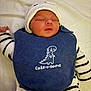 baby, sleeping, bib, dinosaur, hat, striped_clothing, infant, cute, peaceful, lying_down, soft_blanket, white_hat, navy_bib, child, newborn, adorable, face, closed_eyes, small_hands, cozy