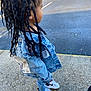 child, denim_jacket, braided_hair, jeans, sneakers, white_shoes, nike, side_view, outdoor, pavement, curious, young_child, fashion, street_style, casual, person, standing, daylight, fence, patches