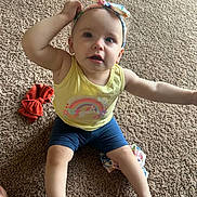 Brittany joined the competition — help win amazing prizes! toddler, child, carpet, yellow_tank_top, headband, bow, rainbow, unicorn, sitting, curious, indoor, clothing, barefoot, expression, person, infant, cute, colorful, playful, young_child