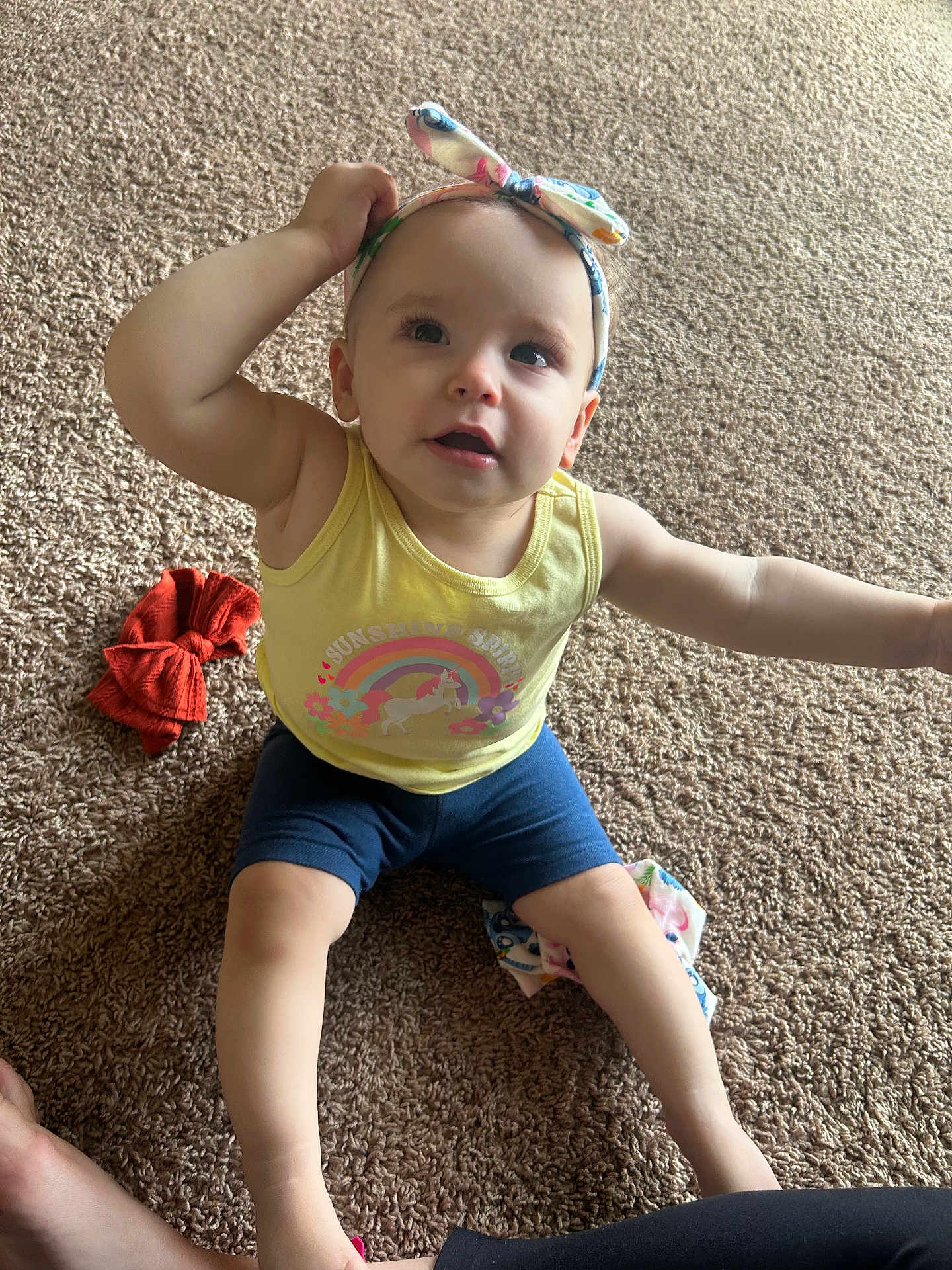 Brittany joined the competition — help win amazing prizes! toddler, child, carpet, yellow_tank_top, headband, bow, rainbow, unicorn, sitting, curious, indoor, clothing, barefoot, expression, person, infant, cute, colorful, playful, young_child