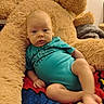 baby, infant, child, portrait, sitting, teddy_bear, stuffed_animal, blanket, turquoise_clothing, fuzzy_texture, wide_eyes, indoors, cozy, colorful, carpet, playroom, nursery, relaxed, face, photography