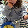 Jade joined the competition — help win amazing prizes! bed, blue_bowl, blue_clothing, bowl, casual_clothing, child, curious_expression, curly_hair, eating, finger_in_mouth, food, indoor, messy_hair, person, scrambled_eggs, snack_time, spoon, striped_bedspread, toddler, young_child