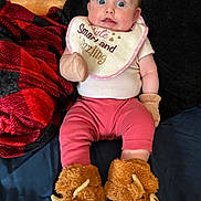 Mariella joined the competition — help win amazing prizes! baby, infant, bib, clothing, slippers, fuzzy, red_blanket, black_blanket, blue_sheet, cute, cozy, face, eyes, person, apparel, sitting, indoor, soft_texture, child, adorable