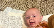 Kayson is registered to the contest to win money with this photo: baby, infant, carpet, diapers, stuffed_toy, plush, hand, face, expression, indoor, floor, soft_surface, clothing, person, child, cute, smiling, toy, lying_down, home
