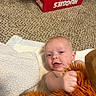 baby, infant, carpet, diapers, stuffed_toy, plush, hand, face, expression, indoor, floor, soft_surface, clothing, person, child, cute, smiling, toy, lying_down, home