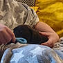 puppy, dog, blanket, person, hand, toy, indoor, cozy, yellow_background, star_pattern, playing, pet, cuddle, comfort, soft_texture, animal, young_dog, resting, warm_colors, close_up