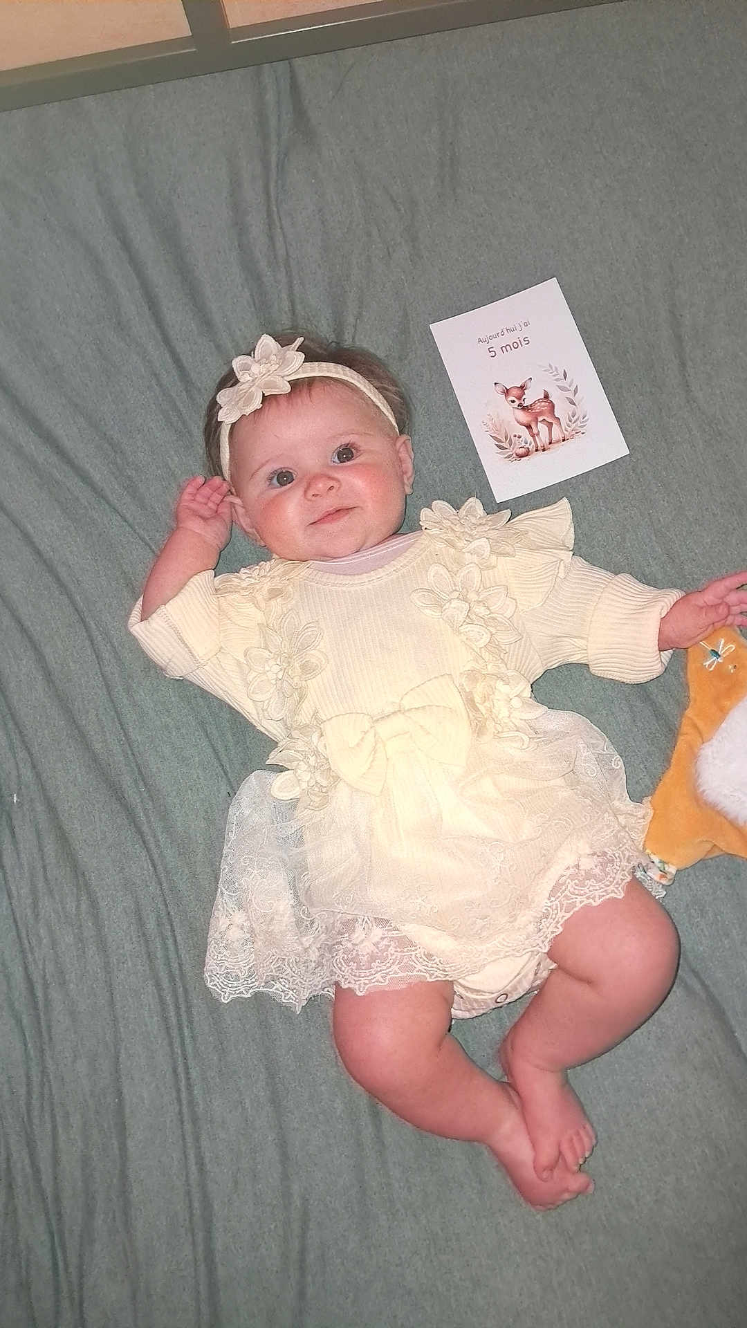 Jade participe au concours pour gagner de l'argent avec cette photo : baby, infant, dress, headband, blanket, plush_toy, smile, face, cute, milestone_card, deer_illustration, lying_down, soft_toys, baby_clothing, indoors, child, happy, portrait, feet, hand