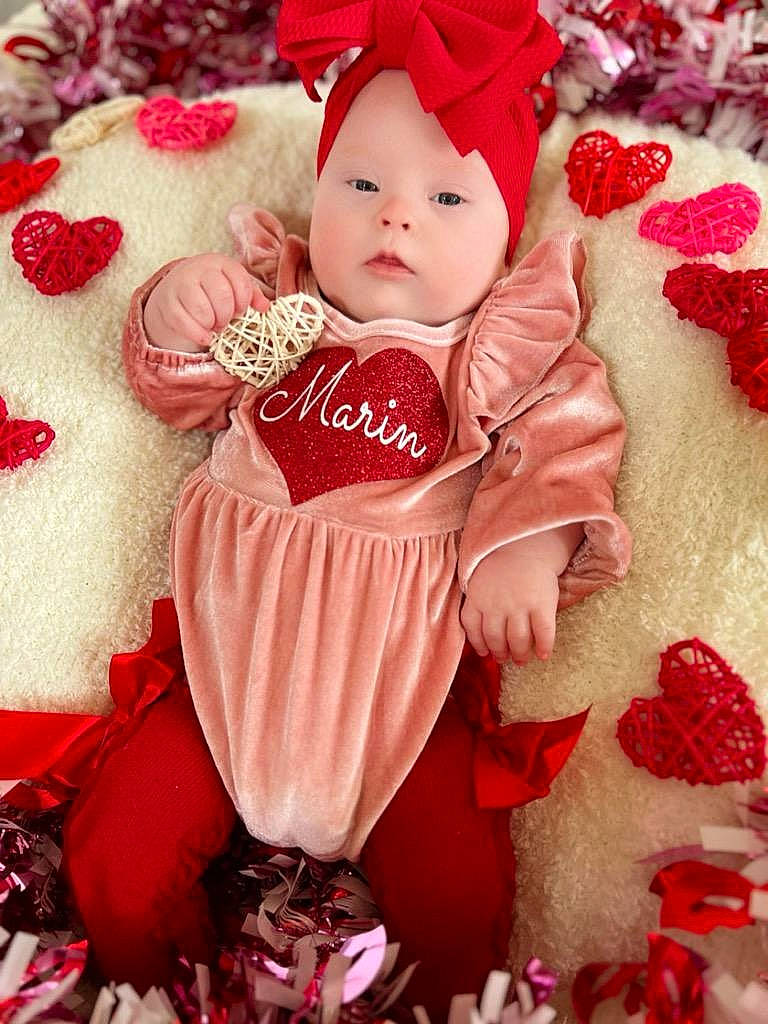 Marin is registered to the contest to win money with this photo: baby, baby_toddler_clothing, carmine, child, christmas, christmas_decoration, christmas_eve, christmas_ornament, costume_hat, event, fictional_character, happy, headwear, holiday, outerwear, pattern, person, pink, red, sleeve