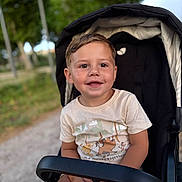 Emilio a rejoint le concours — aidez-le/la à gagner de superbes lots ! child, toddler, stroller, tshirt, smiling, outdoor, park, greenery, happy, cute, face, short_hair, seat, daylight, person, young, nature, casual_clothing, relaxing, portrait