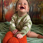 Charlie is registered to the contest to win money with this photo: baby, child, smiling, sweater, plush_pumpkin, green_blanket, autumn_background, indoor, cute, happy, portrait, infant, knitted_clothing, soft_texture, seasonal, fall_colors, baby_hands, baby_feet, crawling, playful