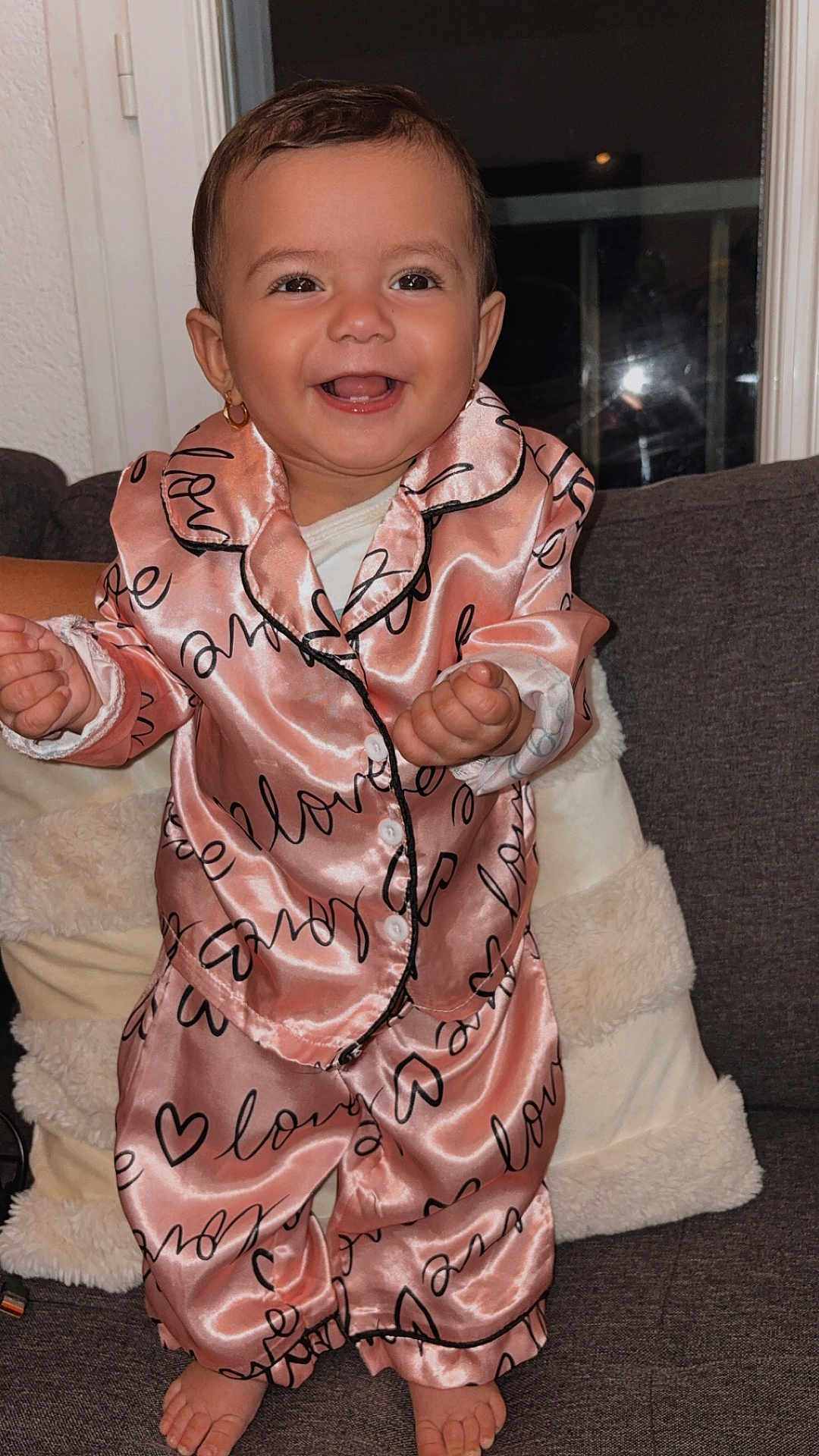 Andréa a rejoint le concours — aidez-le/la à gagner de superbes lots ! baby, toddler, child, smiling, pink_pajamas, satin_fabric, love_pattern, earrings, face, eyes, teeth, hands, toes, couch, throw_pillow, blanket, indoor, portrait, happy, window_reflection