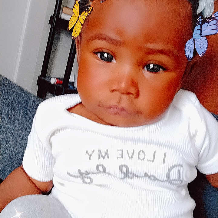 Mi'Ky'ealah America joined the competition — help win amazing prizes! baby, butterfly_filter, casual, child, closeup, cute, digital_filter, expression, face, furniture, gray_pants, head, indoor, person, portrait, room, shelf, sitting, toy, white_shirt