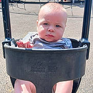 Colton is registered to the contest to win money with this photo: baby, child, swing, playground, outdoor, infant, seat, sunlight, netting, play_equipment, barefoot, expression, person, young_child, summer, daytime, plastic, fun, park, casual