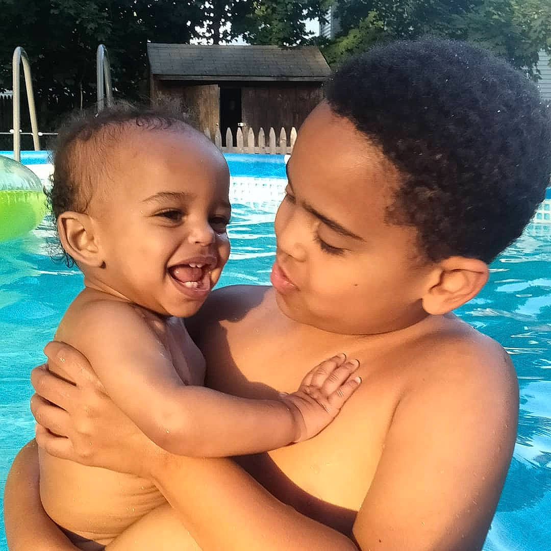 Logan is registered to the contest to win money with this photo: baby, barechested, black, black_hair, chest, chin, eye, face, fun, happy, human_body, joy, leisure, muscle, nose, person, skin, smile, summer, toddler