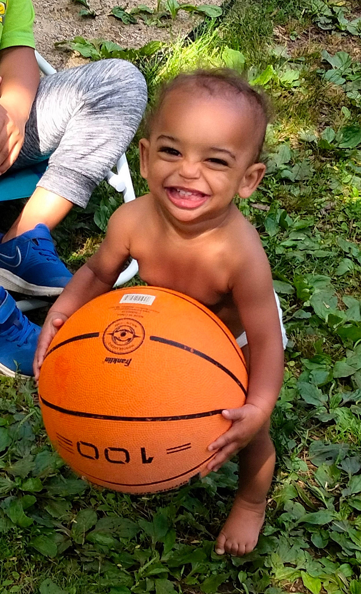 Logan is registered to the contest to win money with this photo: ball, basketball, fun, grass, green, happy, head, human_body, jeans, joy, leisure, people_in_nature, person, plant, shorts, smile, sports_equipment, squash, team_sport, toddler