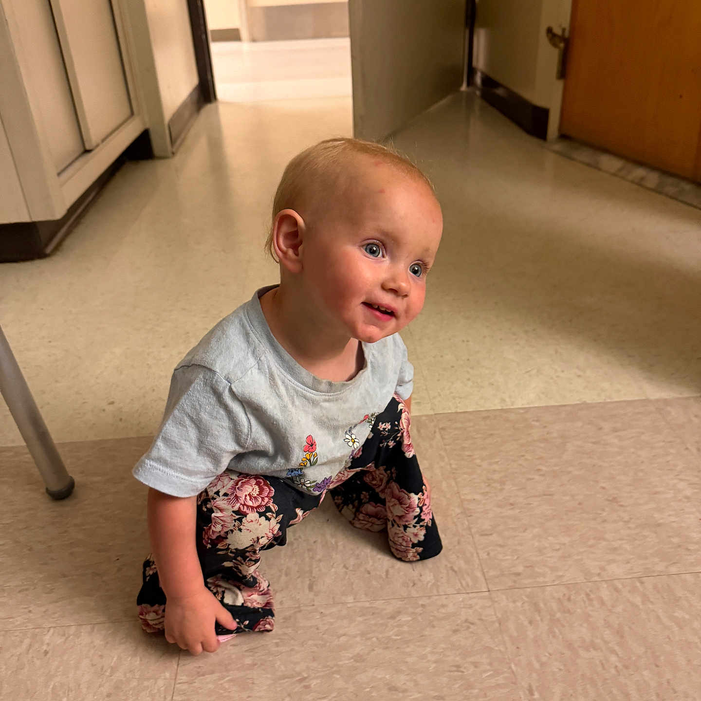 Aurora joined the competition — help win amazing prizes! blue_eyes, cabinet, child, crouching, curious, cute, door, floor, floral_pants, gray_shirt, hallway, happy, indoor, linoleum, person, short_hair, small, smiling, toddler, young_child