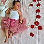 baby, blanket, bow, celebration, cute, feet, flower_arrangement, hand, headband, infant, laying_down, milestone, pink_tutu, plush_toy, red_flowers, skin, soft_texture, white_bunny, white_flowers, white_tank_top