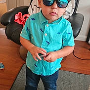 Grayson is registered to the contest to win money with this photo: toddler, child, indoor, standing, cap, sunglasses, turquoise_shirt, dinosaur_print, jeans, sneakers, carpet, chair, furniture, hand_gesture, reflection, casual_clothing, young_child, portrait, home_interior, floor
