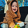 Markas is registered to the contest to win money with this photo: baby, child, toddler, smiling, toy, outdoor, blue_sky, greenery, couch, fuzzy_clothing, hooded_jacket, striped_socks, happy, playful, cute, portrait, sunlight, nature, bright_colors, infant