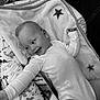 Markas joined the competition — help win amazing prizes! baby, infant, onesie, blanket, star_pattern, dinosaur_print, cushion, smiling, happy, lying_down, black_and_white, toddler, cute, child, soft_texture, indoor, cozy, person, expression, head