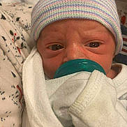 Marshall is registered to the contest to win money with this photo: baby, blanket, child, close_up, cozy, cute, face, hat, indoors, infant, newborn, newborn_baby, pacifier, person, resting, sleepy, soft_light, striped_hat, white_clothes, wrapped