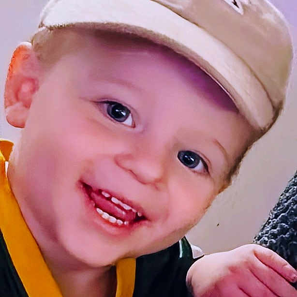 Ezra joined the competition — help win amazing prizes! toddler, child, smiling, cap, hat, face, person, clothing, hand, indoor, portrait, young_child, happy, casual, sleeve, texture, wall, sitting, closeup, cute