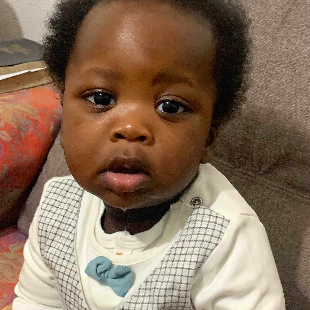 Isayah a rejoint le concours — aidez-le/la à gagner de superbes lots ! baby, bow_tie, child, clothing, couch, curly_hair, cute, drool, expression, face, home, indoor, looking_at_camera, person, portrait, seated, sitting, skin, vest, young_child
