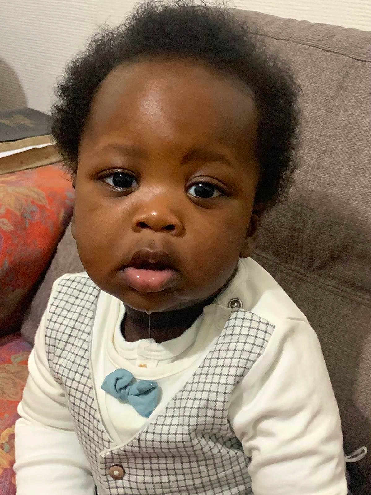 Isayah a rejoint le concours — aidez-le/la à gagner de superbes lots ! baby, child, drool, face, vest, bow_tie, couch, indoor, person, curly_hair, clothing, portrait, seated, expression, cute, young_child, skin, looking_at_camera, sitting, home