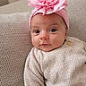 baby, infant, headband, pink_flower, sweater, cozy, couch, textured_fabric, cute, portrait, closeup, child, indoors, soft_lighting, face, eyes, expression, comfortable, relaxed, adorable