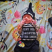 Jared is registered to the contest to win money with this photo: animal_print, baby, bed, blanket, clothing, cute, flamingo, hat, indoor, infant, lion, newborn, patterned_clothes, person, resting, sleeping, small_person, tiger, toddler, zebra