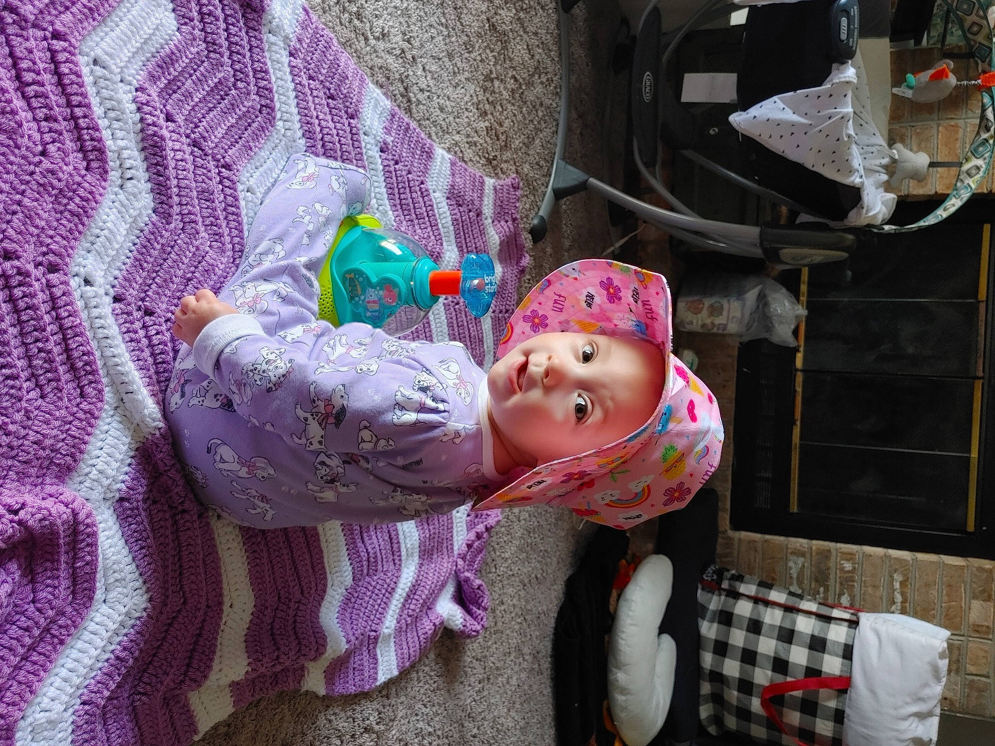 Freya is registered to the contest to win money with this photo: baby, baby_products, baby_toddler_clothing, child, comfort, headwear, helmet, linens, magenta, pattern, person, purple, room, sitting, toddler, tree, violet