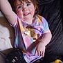 toddler, child, smiling, waving, sitting, colorful_clothing, unicorn, leggings, blanket, couch, indoors, happy, face, hair, hand, cheerful, pattern, fabric, person, casual