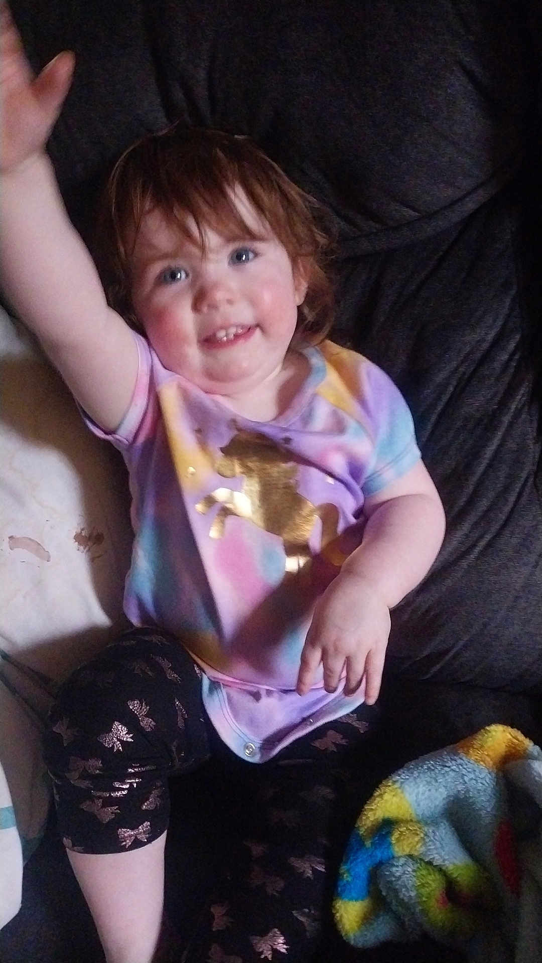 Abigail joined the competition — help win amazing prizes! toddler, child, smiling, waving, sitting, colorful_clothing, unicorn, leggings, blanket, couch, indoors, happy, face, hair, hand, cheerful, pattern, fabric, person, casual