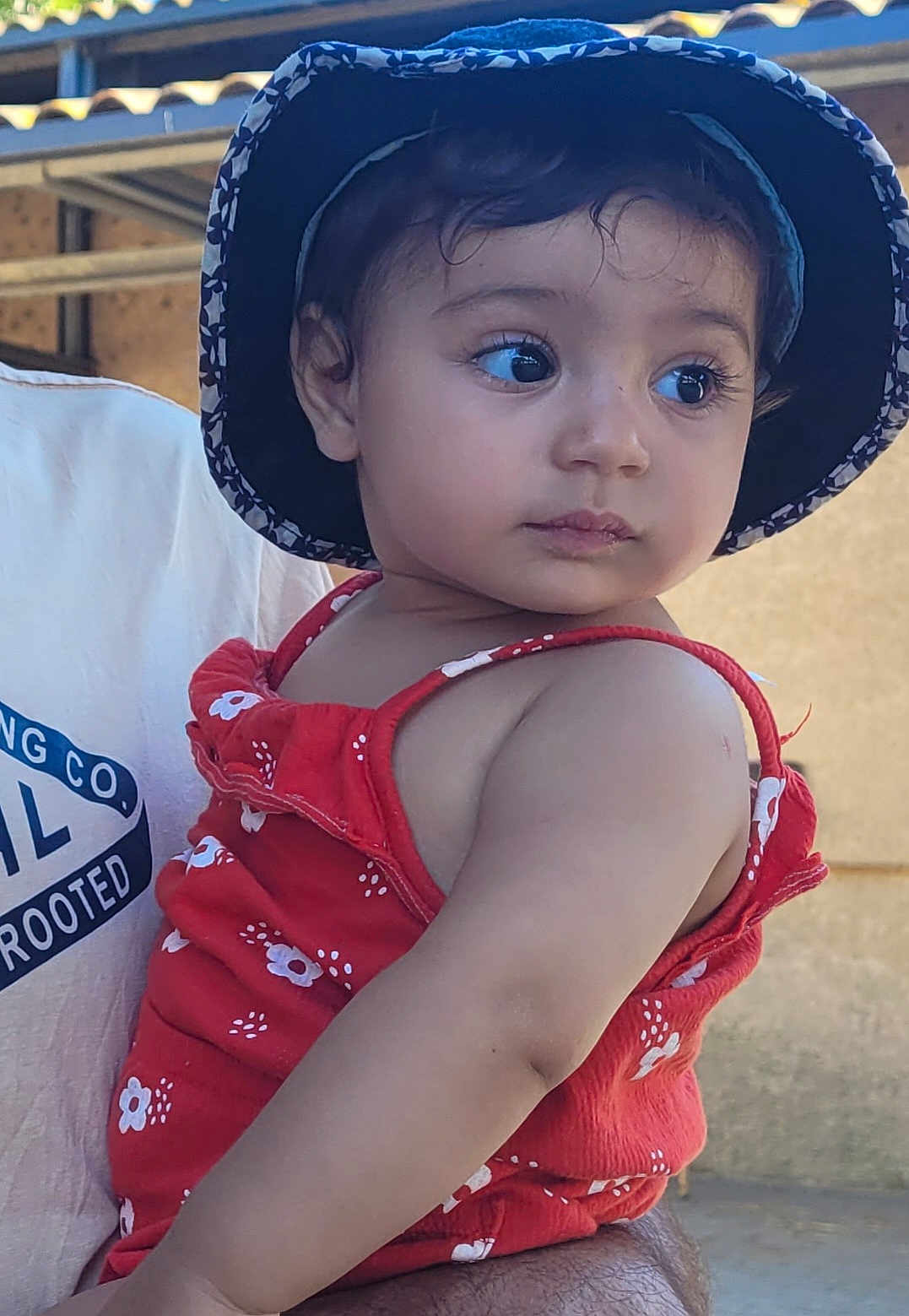 Tasnîm a rejoint le concours — aidez-le/la à gagner de superbes lots ! adult, baby, casual, child, clothing, curious, expression, eyes, face, floral_pattern, hat, holding, outdoor, person, portrait, red_dress, skin, summer, toddler, young_child