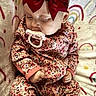 baby, sleeping, pacifier, red_bow, floral_onesie, blanket, rainbow_pattern, infant, cute, peaceful, child, soft_texture, cozy, hand, face, headwear, apparel, rest, indoors, portrait