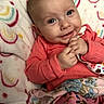 Willow joined the competition — help win amazing prizes! baby, infant, smile, happy, hands, blanket, colorful, coral_clothing, face, eyes, portrait, cozy, patterned_blanket, cute, child, indoor, soft_texture, closeup, newborn, baby_girl