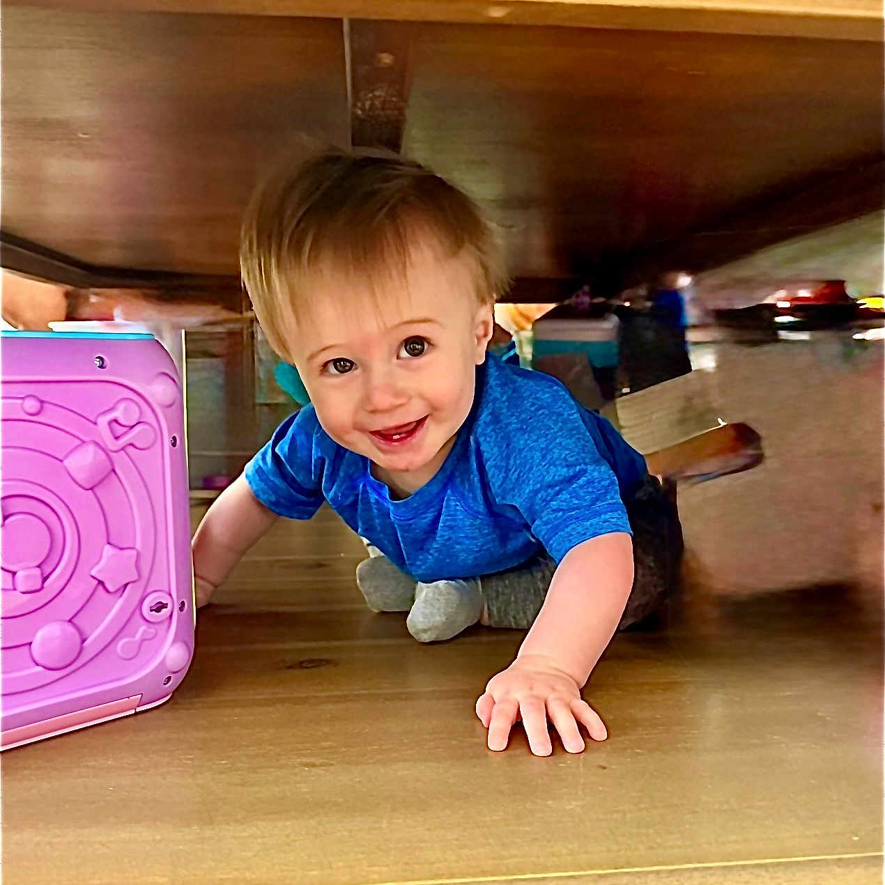 Hudson Paul Wood is registered to the contest to win money with this photo: toddler, child, blue_shirt, crawling, smiling, toy, pink_toy, wooden_table, indoor, floor, playtime, happy, young_child, person, cute, baby, hands, feet, face, home