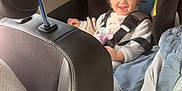Ewen a rejoint le concours — aidez-le/la à gagner de superbes lots ! car_interior, car_seat, child, clothing, curly_hair, fabric, happy, headrest, jacket, parked_cars, person, safety, seat, seatbelt, smiling, sunlight, toddler, transportation, vehicle, window
