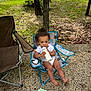 toddler, child, outdoor, grass, tree, gravel, bottle, milk, chair, folding_chair, curly_hair, white_clothing, wipes, nature, park, daytime, relaxing, barefoot, cute, peaceful
