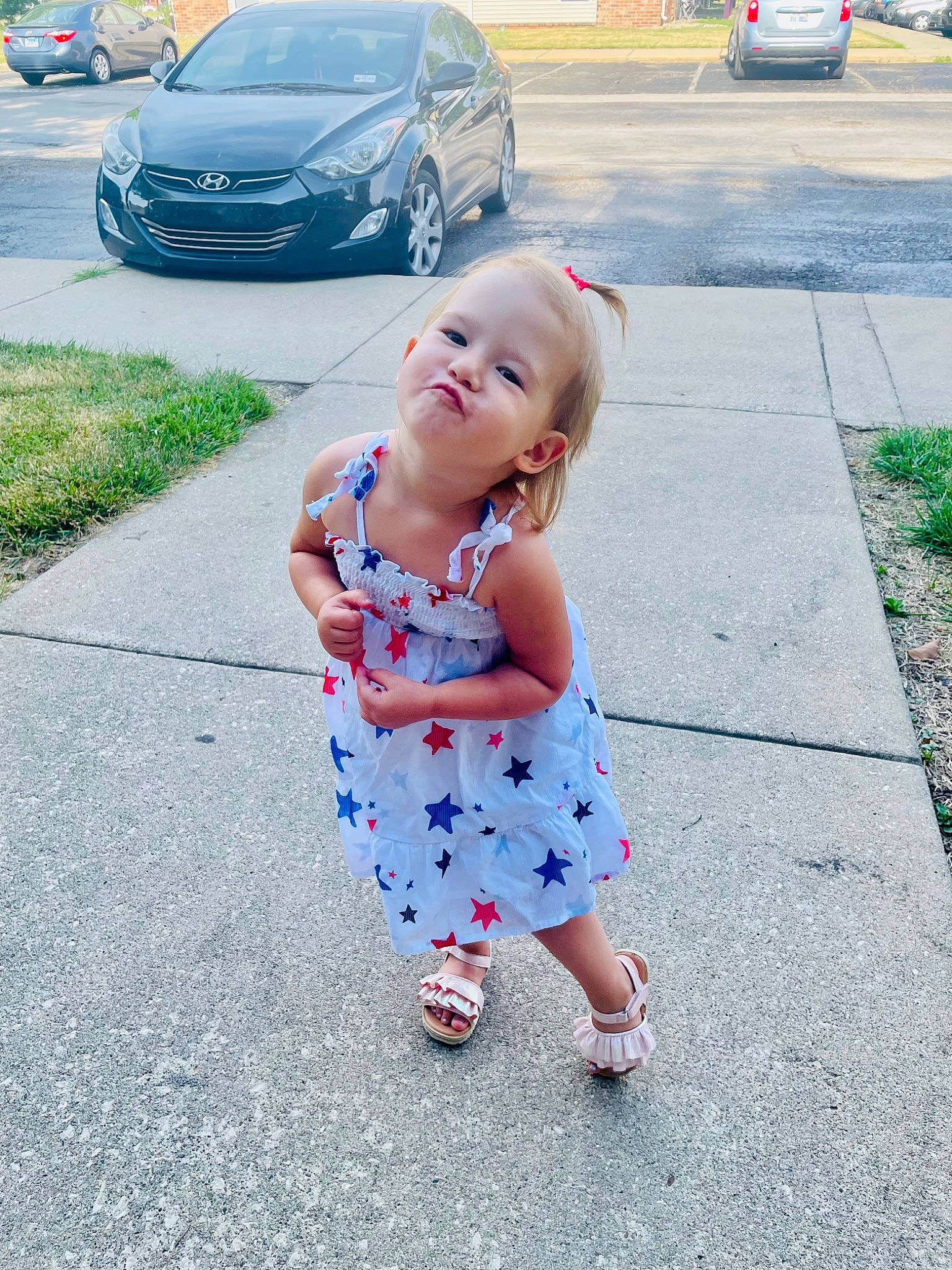 Saige is registered to the contest to win money with this photo: asphalt, automotive_design, automotive_exterior, automotive_tire, baby_toddler_clothing, car, child, electric_blue, grass, infrastructure, morning, motor_vehicle, person, personal_luxury_car, road, road_surface, sidewalk, tire, toddler, vehicle