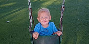 Thaddeus joined the competition — help win amazing prizes! child, toddler, swing, playground, grass, fence, blue_shirt, animal_print_pants, blue_shoes, sunlight, happy, smiling, outdoor, daytime, play, fun, chain, seat, park, nature